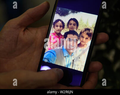 (190710) -- YIWU, July 10, 2019 (Xinhua) -- Photo taken on July 9, 2019 in Yiwu City, east China's Zhejiang Province, shows a picture of Aziz's family on his cellphone screen. Aziz mainly lives in Yiwu City, he only returns to Kabul of Afghanistan for family reunions on major holidays. Aziz Ullah, 41, came to Yiwu City in east China's Zhejiang Province in 2003 with his partners after his graduation from university in his home country Afghanistan. It was his first time to come to Yiwu to shop for smallware. In 2005, Aziz started his own company after being an agent for about 2 years. In recent Stock Photo