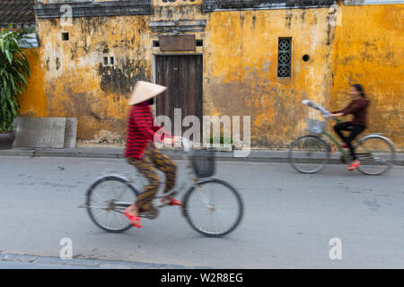 Cyclists on a street in Hoi An, Vietnam. Stock Photo