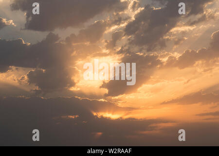 Sunrise with dramatic dark clouds and light rays through clouds at sky, horizontal shot Stock Photo