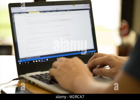 Freelance programmer or developer working at home and typing source code with laptop Stock Photo