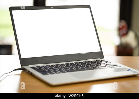 Mockup image of laptop with blank white screen on wooden table in loft cafe Stock Photo