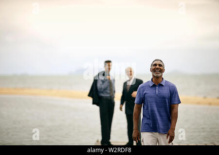 Laughing man walking away from two businessmen. Stock Photo