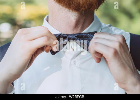 Closeup of man's hand adjusting bow-tie on shirt Stock Photo