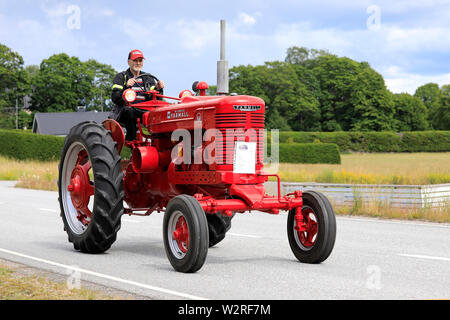 Kimito, Finland. July 6, 2019. Man drives red International Harvester Farmall M tractor, year 1951, on Kimito Tractorkavalkad, vintage tractor parade. Stock Photo