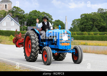 Kimito, Finland. July 6, 2019. Man in traditional costume greets as he drives Fordson Super Major on Kimito Tractorkavalkad, vintage tractor parade. Stock Photo
