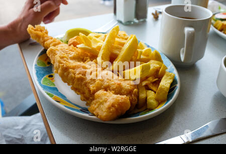 Littlehampton West Sussex UK - Eating freshly cooked cod fish and chips at a harbourside cafe with a cup of tea Stock Photo