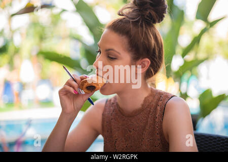 A young female student eating a bun of bread stuffed with chocolate - Close-up Stock Photo