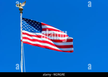 American flag at the Golden Gate National Cemetery, San Bruno, California, USA. Isolated on blue background. Stock Photo