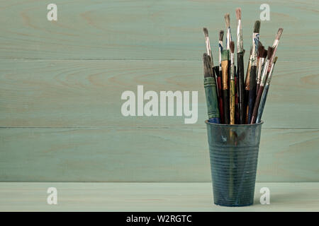 Assorted dirty painting brushes in plastic flask Stock Photo