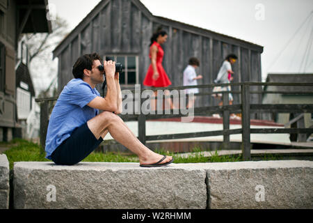 Man looking through binoculars at wharf. Stock Photo
