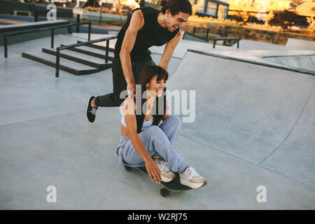 Young man and woman having fun with skateboard in the skate park. Couple skateboarding at skate park. Stock Photo