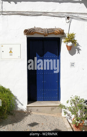 Typical blue painted door with decorative potted plants on a white washed wall in Frigiliana, Province of Málaga, Spain. Stock Photo