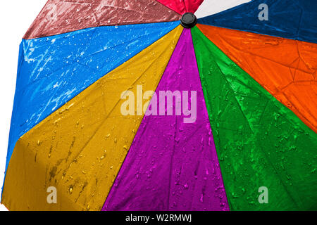 Wet multicolored umbrella close up image on isolated background. Waterproof fabric cloth with water drops and splashes. Rainbow vivid colors. Good or Stock Photo