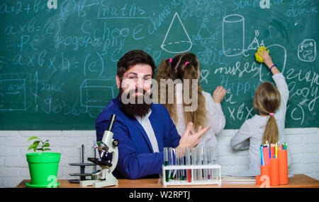 Explaining biology to children. How to interest children study. Fascinating biology lesson. School teacher of biology. Man bearded teacher work with microscope and test tubes in biology classroom. Stock Photo