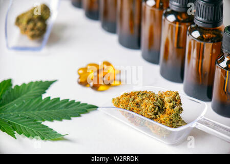 Assorted cannabis products including cannabis tincture or CBD oil, dried nugs and capsules isolated over white, medical marijuana concept Stock Photo