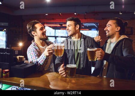 Meeting friends at the bar. Friends drink beer, talk, laugh at the bar in the pub. Stock Photo