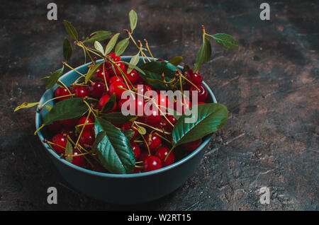 Cherries in blue bowl on an old table. Stock Photo