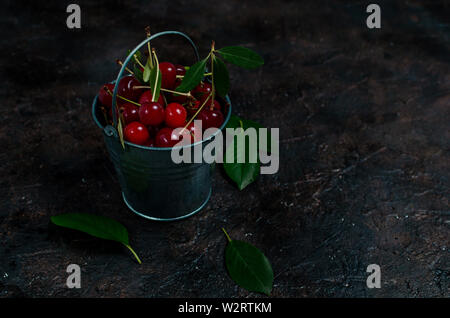 Cherry berry in a small decorative bucket on the old village,concrete floor. Stock Photo
