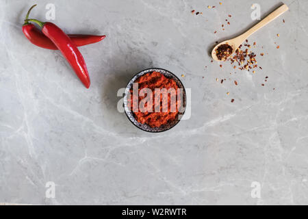 Traditional Maghrebi hot chili pepper sauce harissa on a grey marble background. Arabic cuisine. Adjika Hot Pepper Sauce. Peperoncini calabrese with o Stock Photo