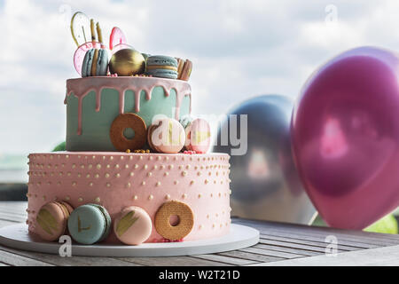 Colourful Fresh Macaroons on pastel cake in many levels on natural wooden background. Sweets concept. Stock Photo