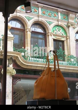 Photo of a designer leather handbag in front of the ornate interior decoration of the upmarket County Arcade, a luxury shopping destination in Leeds Stock Photo