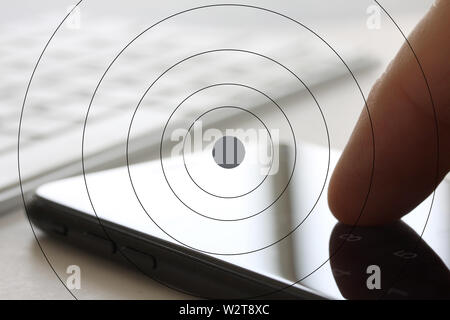 Smartphone with finger touching the screen and keybord in background. Selective focus and extreme close up and hard contrast fading out for copy writi Stock Photo