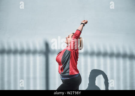Morning yoga. Side view of young plus size woman in sports clothing stretching while warming up outdoors. Weight losing. Sport concept Stock Photo