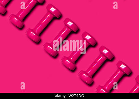 Row of pink dumbbells on pink background. Health care concept. Flat lay. Stock Photo