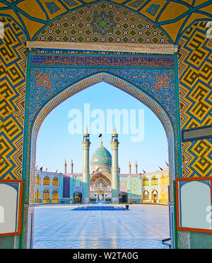 The ornate arch with complex tile traceries opens the view on the minarets and bulbous dome of Imamzadeh Helal Ali Holy Shrine, Aran o Bidgol, Iran Stock Photo