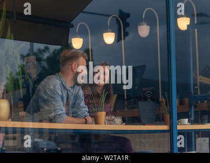two friends talking in a cafe. Shot through window. Stock Photo
