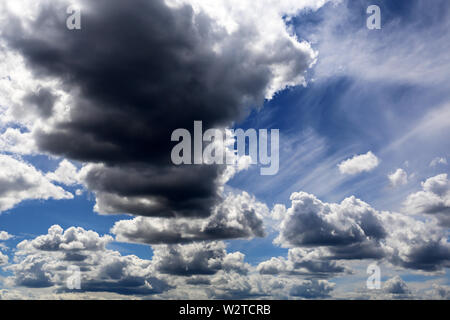 Storm cloud on blue sky covered with white cumulus and cirrus clouds. Summer cloudscape, beautiful background for good weather before the rain Stock Photo