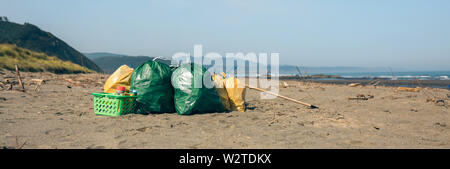 Garbage bags and utensils on the beach after doing a cleaning Stock Photo