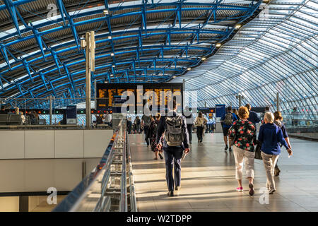 WATERLOO STATION TRAVELLERS new architecture platform additions 20-24 in former Eurostar Terminal. Modern busy departures concourse with rail travellers commuters in late afternoon sun, network information screens in background Waterloo Station London SE1 Stock Photo