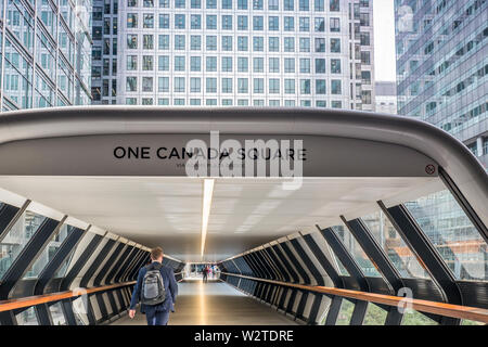 Adams Plaza Bridge from Crossrail Place leading to iconic One Canada Square Tower with office City worker in suit crossing. Canary Wharf London E14