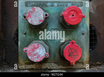 A standpipe connection with four pipes with red caps on the side of a building Stock Photo