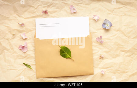 Mockup white greeting card and envelope with hydrangea flowers on paper background. Copy space for text. Stock Photo