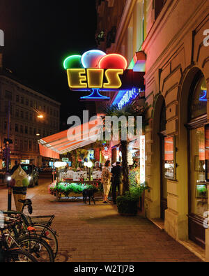 People ordering ice cream beneath a neon sign in Vienna, Austria at night Stock Photo
