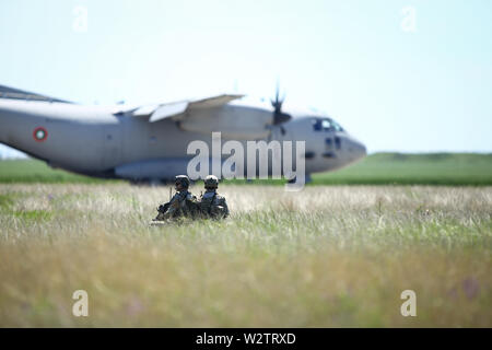 Boboc, Romania - May 22, 2019: Romanian army soldiers patrol on a military air base, with an Alenia C-27J Spartan military cargo plane from Stock Photo