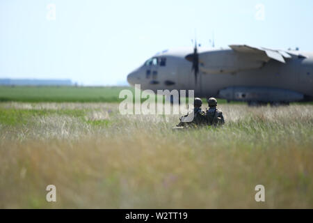 Boboc, Romania - May 22, 2019: Romanian army soldiers patrol on a military air base, with an Alenia C-27J Spartan military cargo plane from the Bulgar Stock Photo