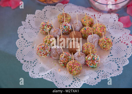 Sweet candies on the dessert table . Balls of biscuit on a stick loli pop. cake pop. candy bar . Delicious and tasty dessert table with cupcakes . lit Stock Photo