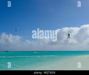 Tourists kitesurfing jumping in the air and taking off on the turquoise lagoon of Aitutaki, Cook Islands, Polynesia Stock Photo