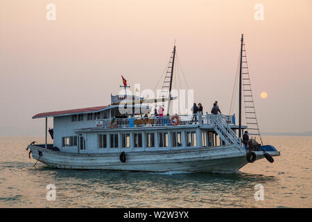 Halong Bay, Vietnam - December24, 2013:  Tourist boat navigating at Halong Bay with a few people regarding the sunset. Stock Photo