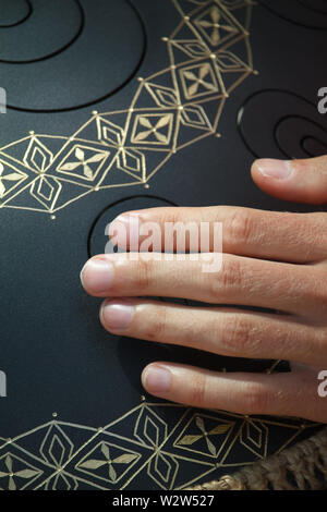 Closeup of a mans hand playing on modern musical instrument Hand pan or Vadjraghanta or metal tongue drumon, selective focus Stock Photo