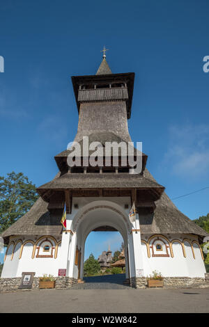 Looking through unique entrance with very high, wooden shingle roofed tower to the grounds of Barsana Monastery, Maramures, Romaina Stock Photo