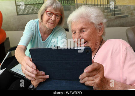 Kassel, Germany. 26th June, 2019. Rosemarie Fischer (l, 81) and Gisela Bossecker (95) deal with their tablet in the Käthe-Richter-Haus retirement home. In retirement homes, the Internet had a niche existence. But nursing homes are rethinking - also because their clientele is changing. Credit: Uwe Zucchi/dpa/Alamy Live News Stock Photo