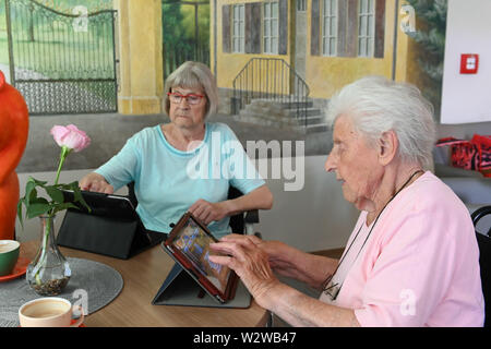 Kassel, Germany. 26th June, 2019. Rosemarie Fischer (l, 81) and Gisela Bossecker (95) deal with their tablet in the Käthe-Richter-Haus retirement home. In retirement homes, the Internet had a niche existence. But nursing homes are rethinking - also because their clientele is changing. Credit: Uwe Zucchi/dpa/Alamy Live News Stock Photo