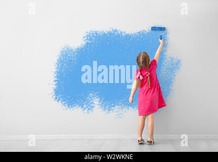 Little girl painting wall in room Stock Photo