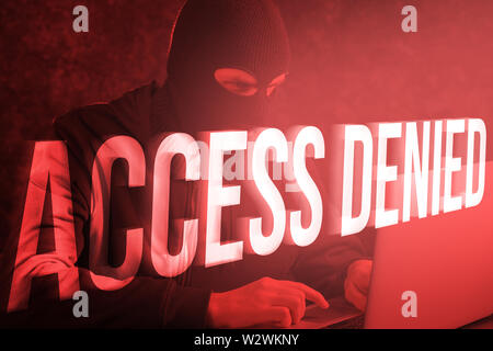 Male hacker with laptop and text ACCESS DENIED on color background Stock Photo
