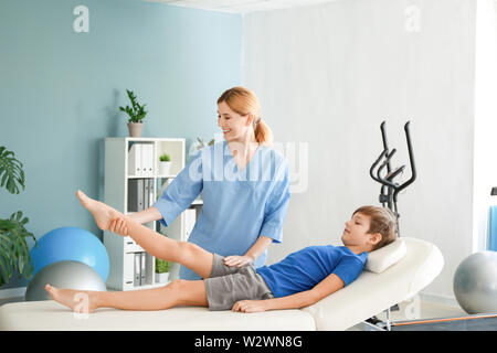 Physiotherapist working with little boy in rehabilitation center Stock Photo