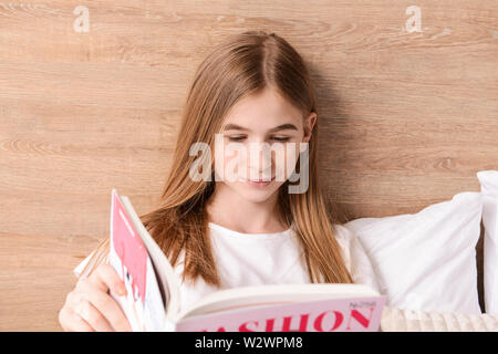 Cute teenage girl reading fashion magazine in bedroom at home Stock Photo